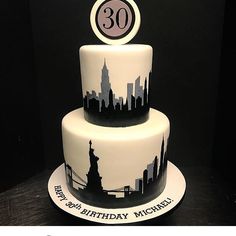 a three tiered birthday cake with the number 30 on it's side and an empire building in the background