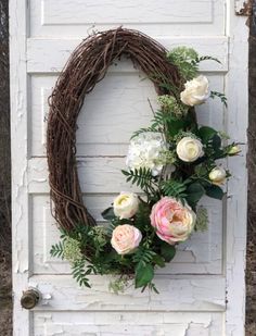 a wreath is hanging on the side of a door with white and pink flowers in it