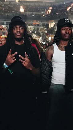 two young men standing next to each other in front of a crowd at a concert