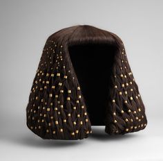 a brown wig with gold squares on the front and sides, sitting against a gray background