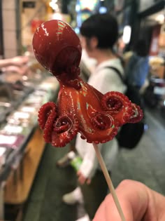 an octopus lollipop is being held up in front of a man at a store