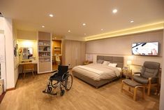 a bedroom with a bed, chair and television in it's center area is shown