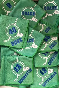 green towels with blue and white logos on them are stacked up in a pile next to each other