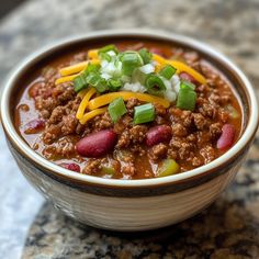 a bowl of chili with cheese and green onions