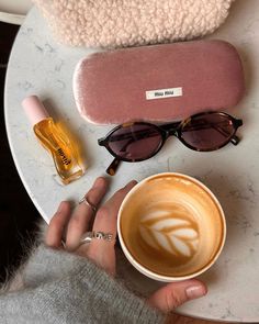 a woman holding a cup of coffee next to her eyeglass case