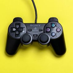 a close up of a video game controller on a yellow surface with wires attached to it
