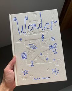 a hand holding up a book with writing on it that reads wonder and an airplane