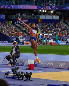 a woman jumping in the air on top of a track