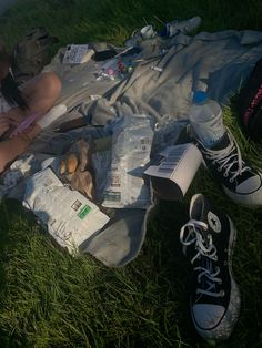 a woman sitting on the grass with her feet up next to food and water bottles
