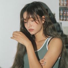 a woman with long hair is holding her hand near her face