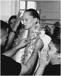 a black and white photo of a woman getting her hair styled by another person in the background