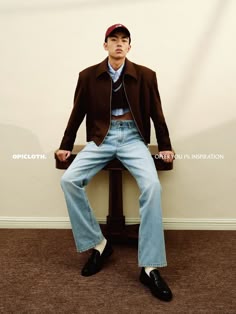 a young man sitting on top of a wooden table wearing jeans and a baseball cap