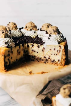 a cheesecake with chocolate chip cookies and whipped cream is cut in half on a cutting board