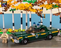 a lego police car is shown in front of some trees and other toy figures on the ground