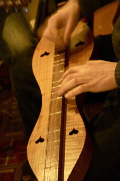 a close up of a person playing an instrument with one hand on the guitar strings
