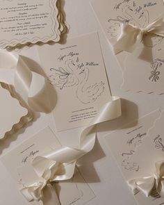 the wedding stationery is laid out on top of each other with ribbons and bows