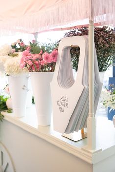 a flower bar with flowers in white vases and pink carnations behind it