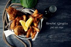 some fried food is on a plate with french fries and lemon wedges