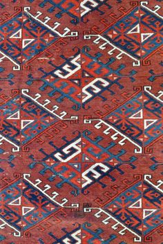 an old red rug with blue, white and red designs on the bottom half of it