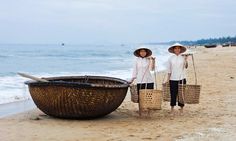 two people standing on the beach with baskets