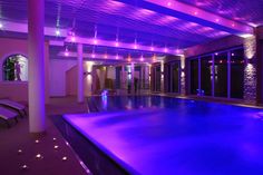 an indoor swimming pool lit up with purple lights