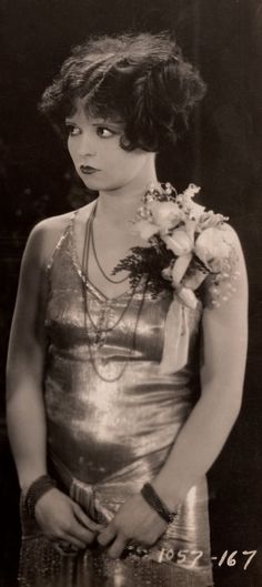 an old black and white photo of a woman wearing a dress with flowers in her hair