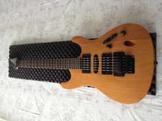 an electric guitar laying on top of a white sheet covered bed with black buttons and strings