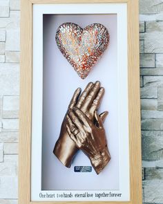 two golden hands and a heart in a frame