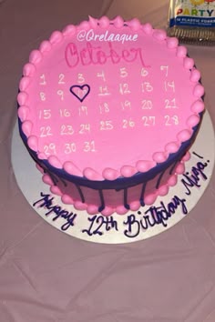 a birthday cake with pink frosting and purple icing is on top of a table