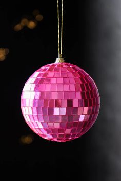 Christmas tree decoration of a hot pink disco ball bauble hanging on a gold string.