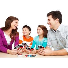 a group of people sitting around a table with cards in front of them and smiling at each other