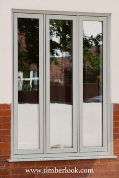 the cat is laying on the window sill in front of the brick wall and tree