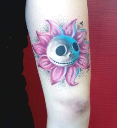 a tattoo with a skull and flower on the arm, it looks like an alien face