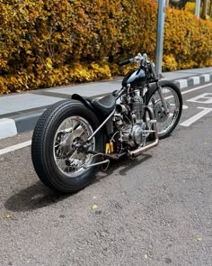 a motorcycle is parked on the side of the road in front of bushes and trees