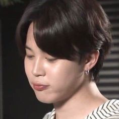 a close up of a person with short hair and wearing a striped shirt looking at something