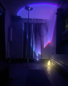 a room with a purple light coming from the ceiling and curtains on the window sill