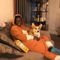 a man sitting on a couch holding a dog in his lap and smiling at the camera