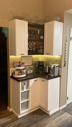 this kitchen has white cabinets and black counter tops with baskets on the bottom, along with an open pantry door