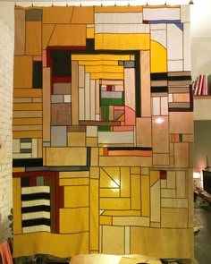 a large piece of art hanging on the side of a wall next to a table