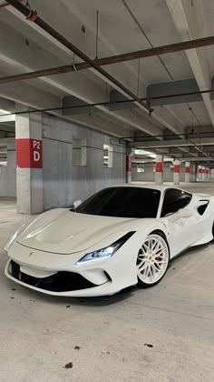 a white sports car is parked in a parking garage with no one around it,