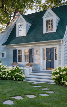 a blue house with white flowers in the front yard and steps leading up to it