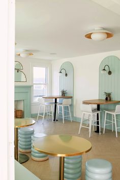 the interior of a restaurant with tables and stools in pastel blue, white and gold colors