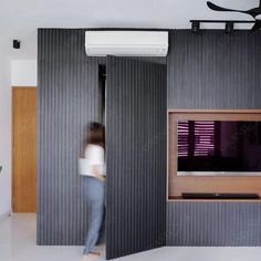 a woman standing in front of a tv inside of a room with sliding doors on both sides