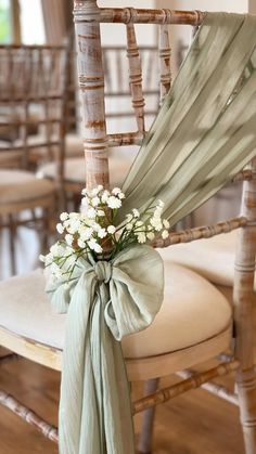 a chair with a bow tied around it and flowers on the back of it's seat
