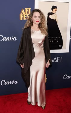 a woman in a long dress standing on a red carpet