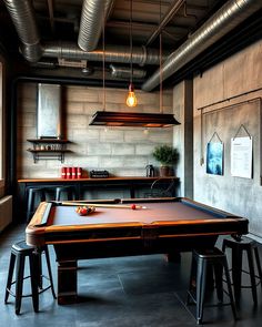 a pool table and stools in a room with exposed pipes on the ceiling,