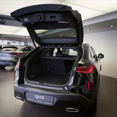 the back end of a car with its trunk open in a showroom filled with other cars
