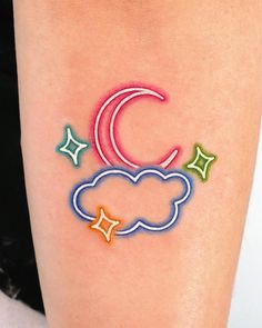 a woman's arm with a colorful cloud and stars tattoo on it