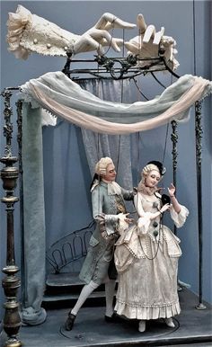 two figurines are standing in front of a bed