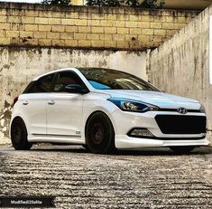 a white car parked in front of a brick wall
